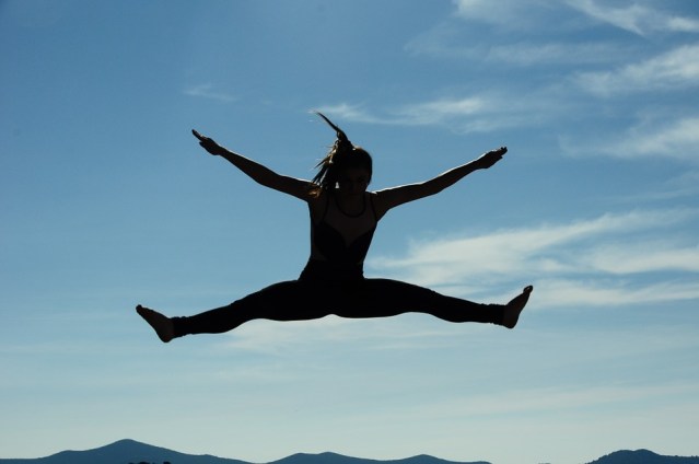 Silhouette of a woman joyfully leaping, widespread arms and legs