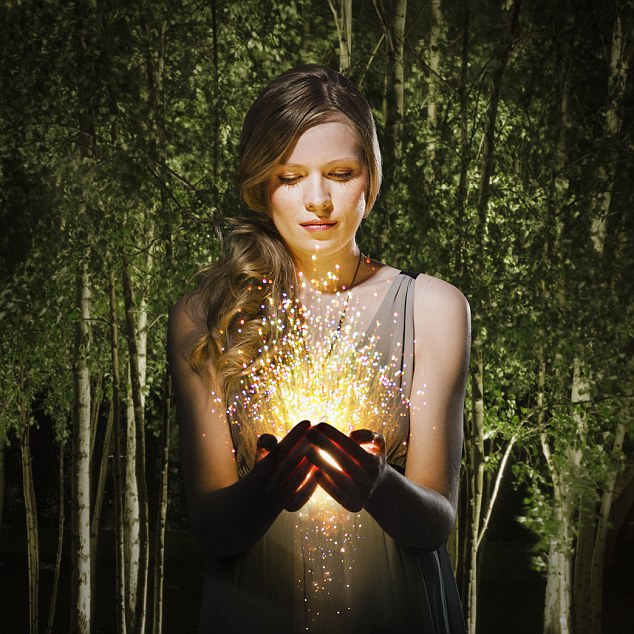 woman in the forest looking at sparklers in her hands