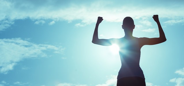 woman showing strength with biceps, bright blue sky and clouds behind her.