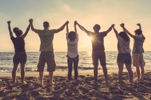 A family on the beach all holding hands together in the air