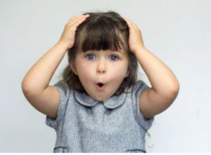 Girl child with hands on head looking at the camera saying wow