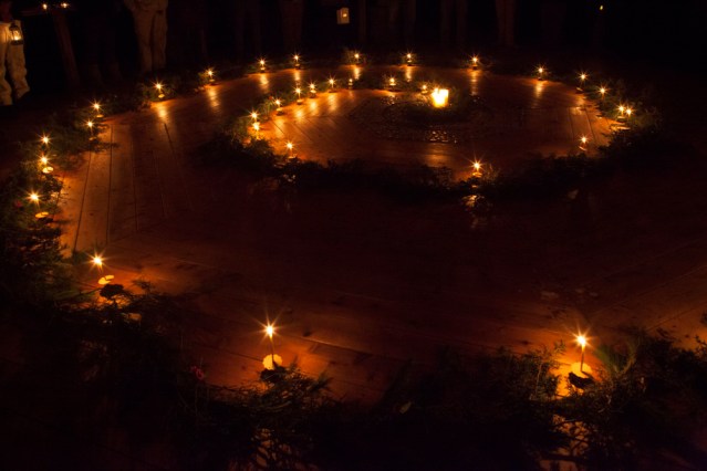 candles and evergreen boughs making a winter spiral on a wood floor.