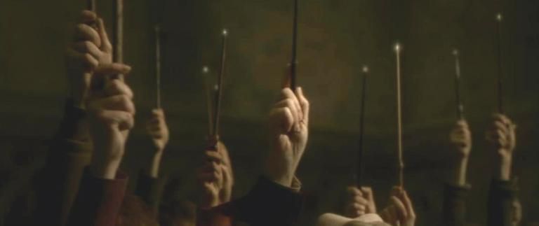 a crowd of hands raising lit wands from Harry Potter