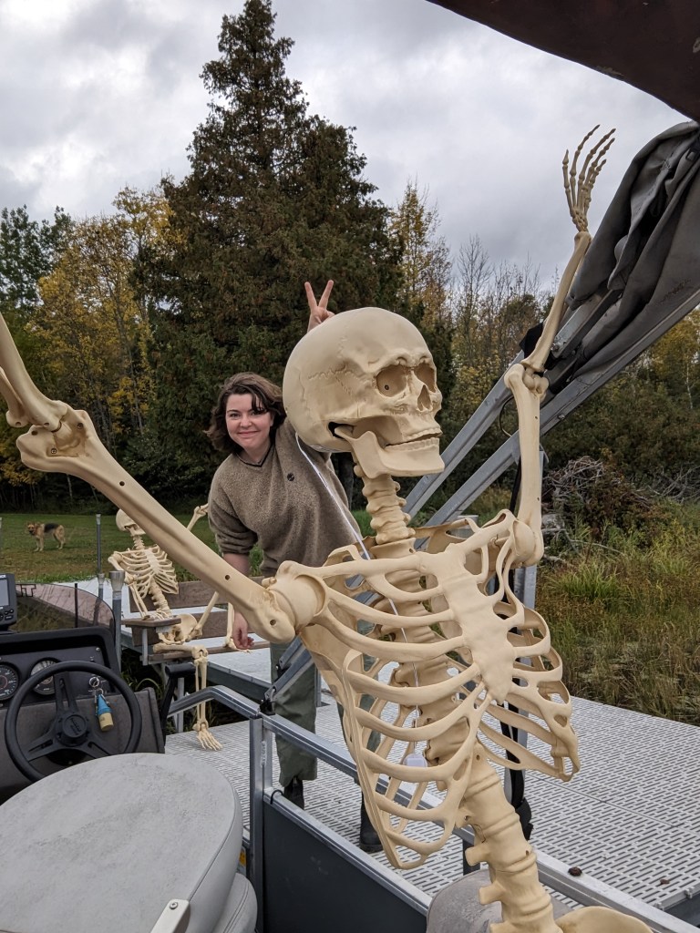 the author's niece behind a poseable skeleton, giving it rabbit ears with the peace sign