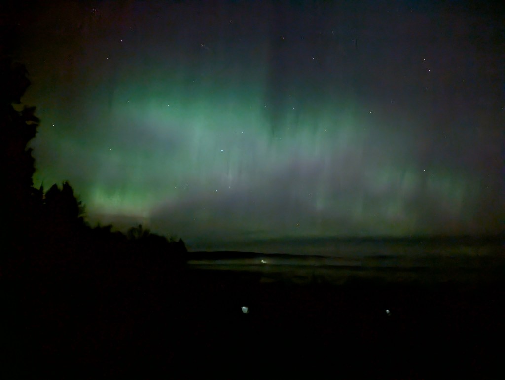 green and purple streaking northern lights over a lake